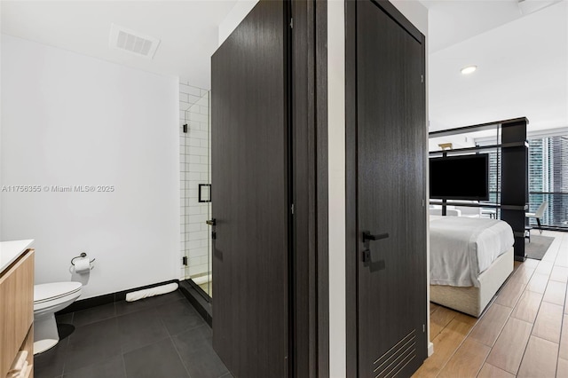 full bathroom featuring a stall shower, visible vents, baseboards, toilet, and ensuite bath