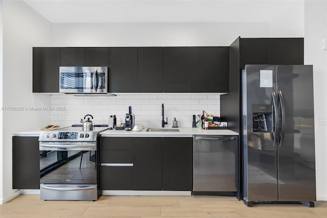 kitchen featuring stainless steel appliances, light countertops, dark cabinetry, and a sink