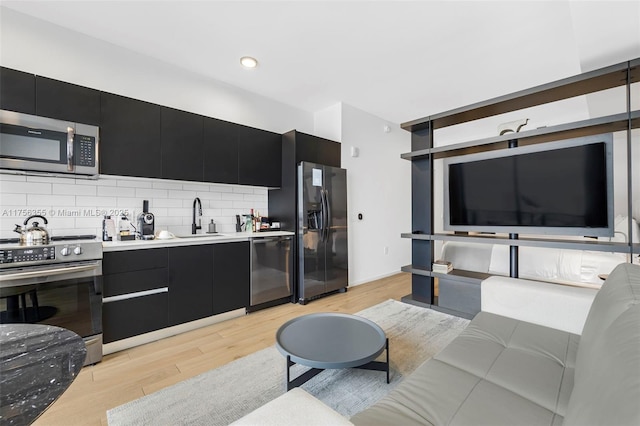 kitchen featuring a sink, backsplash, stainless steel appliances, and dark cabinetry