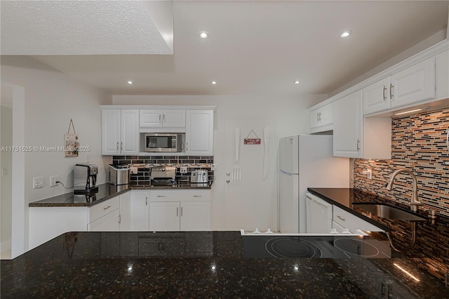 kitchen with white appliances, white cabinetry, backsplash, and a sink