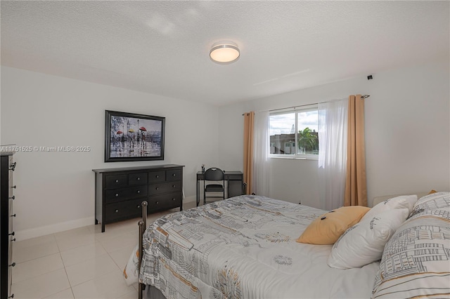 bedroom featuring a textured ceiling, light tile patterned flooring, and baseboards