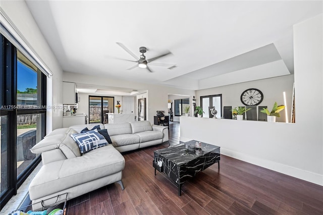 living area featuring a ceiling fan, wood finished floors, visible vents, and baseboards