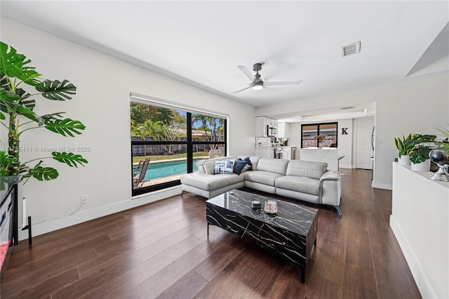 living room featuring a ceiling fan, dark wood-style flooring, visible vents, and baseboards