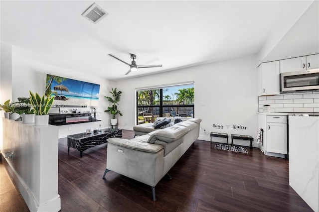 living area featuring dark wood-style floors, baseboards, visible vents, and a ceiling fan