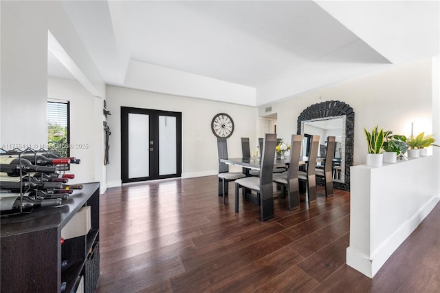 dining space featuring baseboards, a raised ceiling, wood finished floors, and french doors