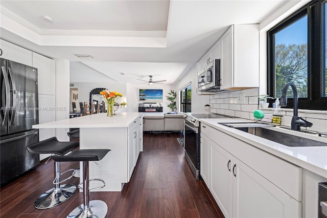 kitchen featuring tasteful backsplash, dark wood finished floors, a breakfast bar, stainless steel appliances, and a sink