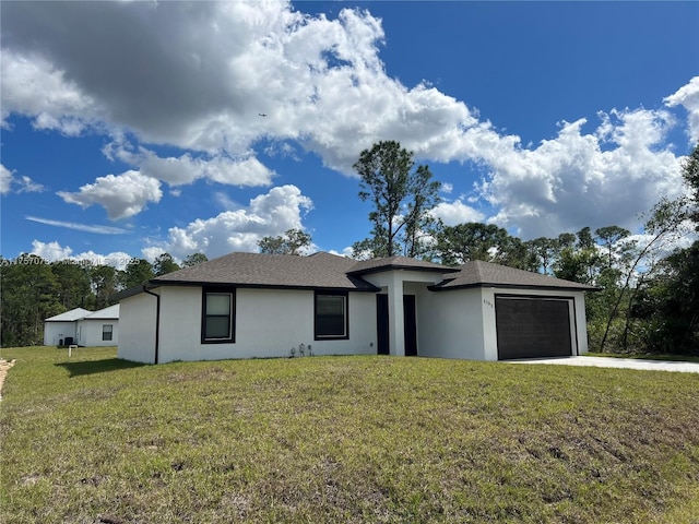 view of front of house with a front yard, concrete driveway, an attached garage, and stucco siding