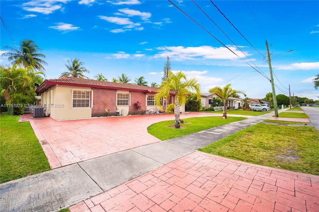 ranch-style house with stucco siding, central AC unit, fence, a tiled roof, and a front lawn