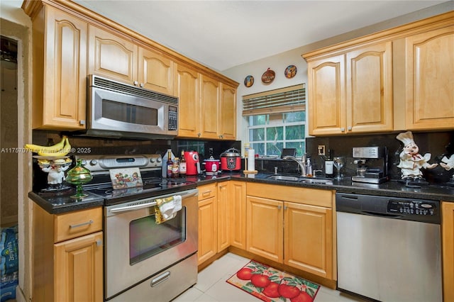 kitchen featuring dark stone counters, stainless steel appliances, tasteful backsplash, and a sink