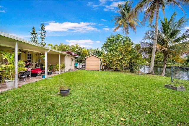 view of yard featuring ceiling fan, an outbuilding, fence, a storage unit, and a patio area