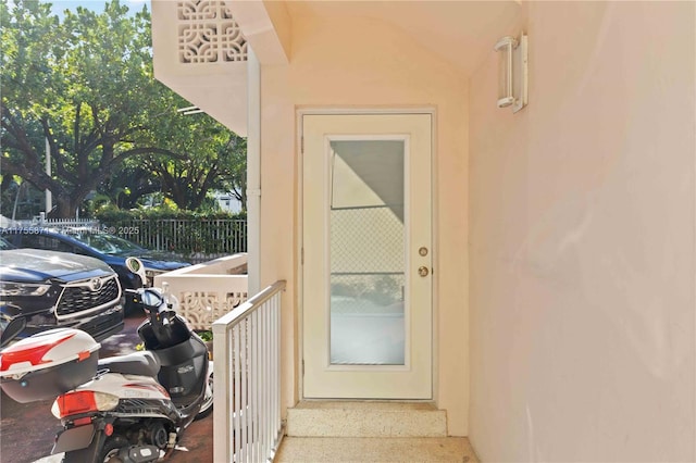 doorway to property featuring fence and stucco siding