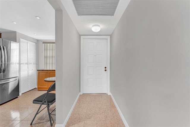 doorway featuring light tile patterned floors, visible vents, and baseboards