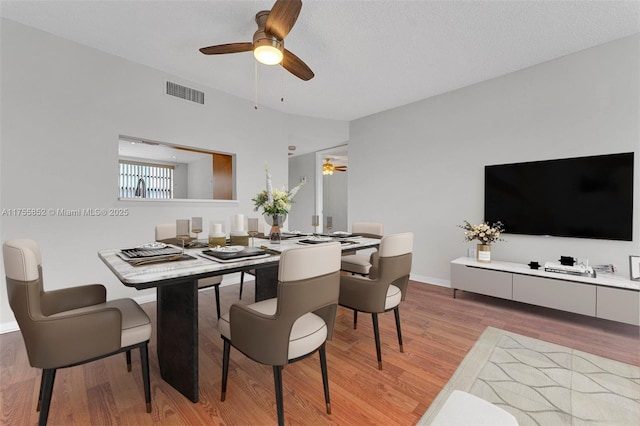 dining area featuring ceiling fan, a textured ceiling, visible vents, baseboards, and light wood-type flooring