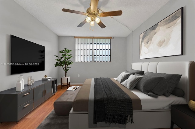 bedroom featuring a textured ceiling, ceiling fan, lofted ceiling, baseboards, and light wood-type flooring