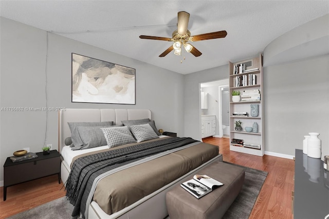 bedroom featuring a ceiling fan, baseboards, ensuite bath, and wood finished floors