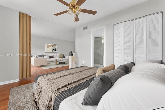 bedroom featuring visible vents, ensuite bath, ceiling fan, wood finished floors, and a closet