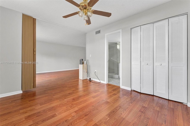 unfurnished bedroom featuring a closet, visible vents, ceiling fan, wood finished floors, and baseboards