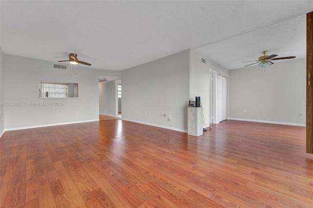 unfurnished living room with ceiling fan, wood finished floors, visible vents, and baseboards