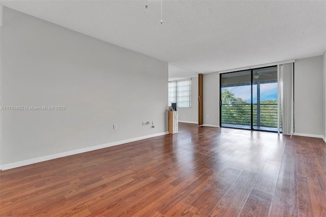 empty room featuring a wealth of natural light, floor to ceiling windows, and wood finished floors