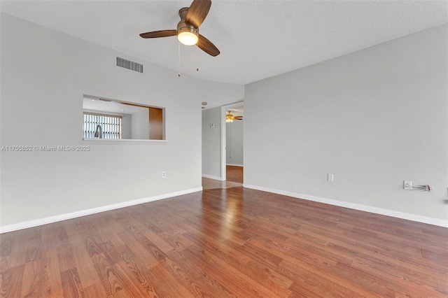 empty room featuring baseboards, visible vents, ceiling fan, and wood finished floors