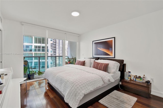 bedroom featuring expansive windows, dark wood-style flooring, and baseboards