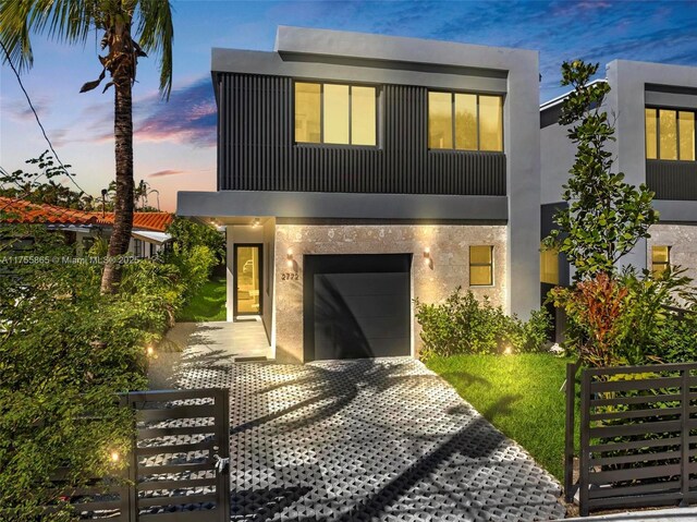 modern home featuring a fenced front yard, decorative driveway, an attached garage, and stucco siding