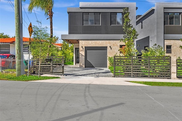 contemporary house featuring driveway, an attached garage, fence, and stucco siding