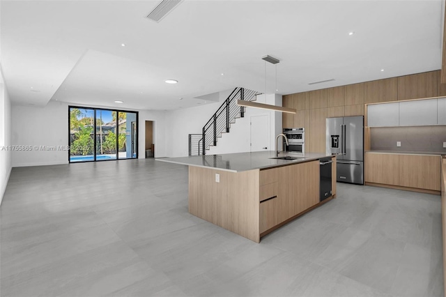 kitchen with an island with sink, high quality fridge, modern cabinets, open floor plan, and a sink