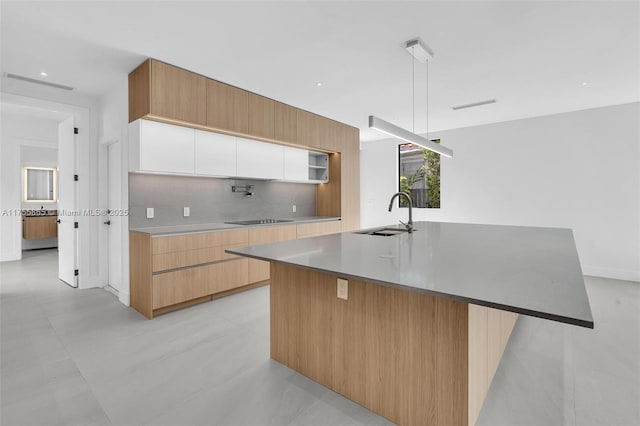 kitchen with black electric stovetop, modern cabinets, a sink, and decorative backsplash