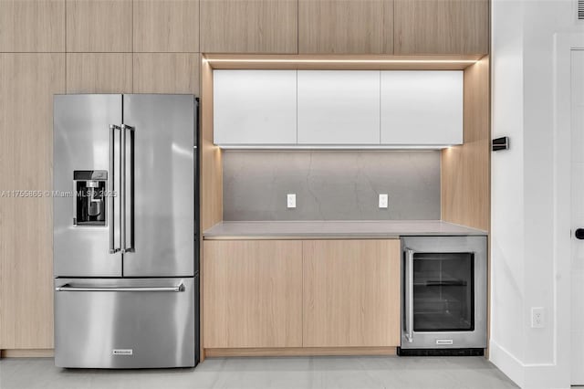 kitchen featuring wine cooler, high end fridge, light countertops, light brown cabinetry, and modern cabinets