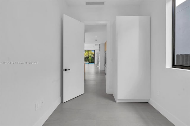 hallway featuring baseboards, concrete floors, and visible vents