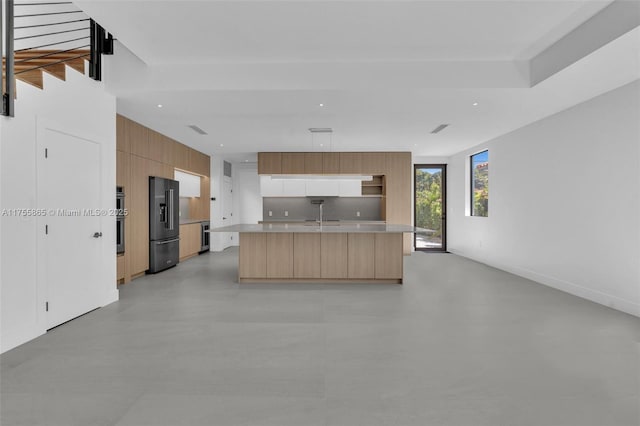 kitchen with stainless steel double oven, light countertops, black fridge, backsplash, and modern cabinets