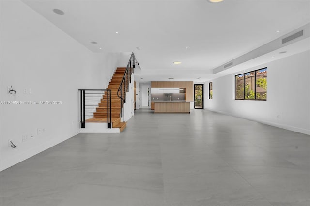 unfurnished living room featuring recessed lighting, visible vents, and stairs