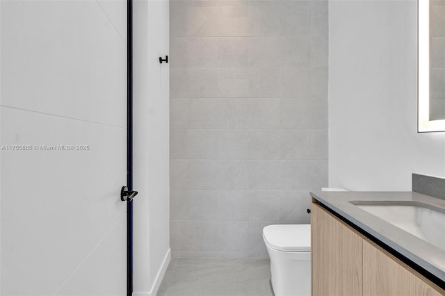 bathroom with tile walls, vanity, and toilet