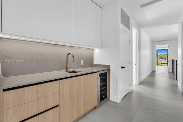 kitchen featuring beverage cooler, light brown cabinets, a sink, and modern cabinets