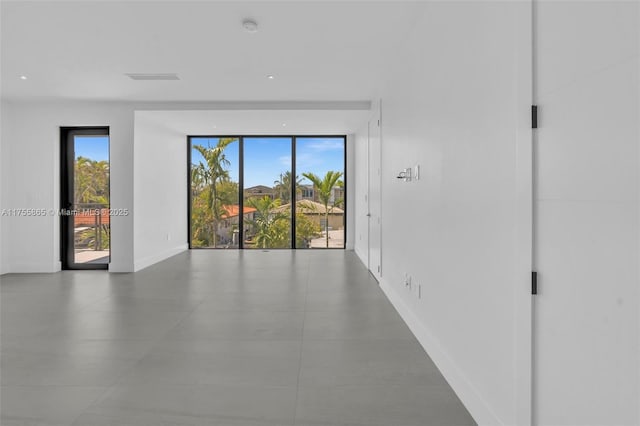 empty room featuring baseboards, a wealth of natural light, and floor to ceiling windows