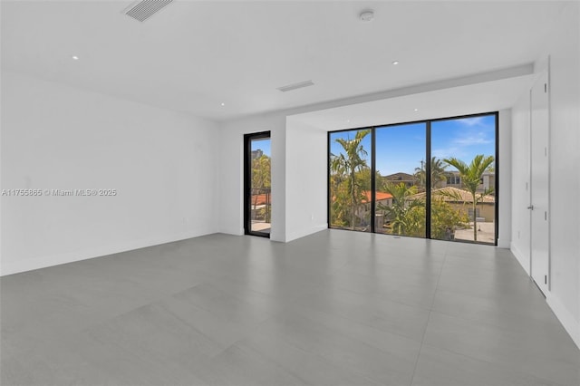 spare room with a wealth of natural light, visible vents, and baseboards