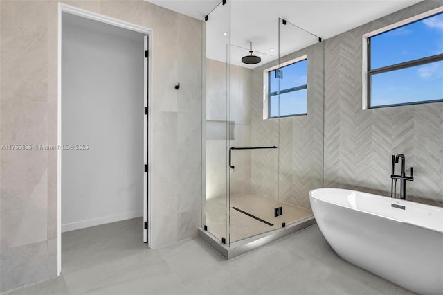 bathroom featuring a shower stall, a freestanding bath, and tile walls