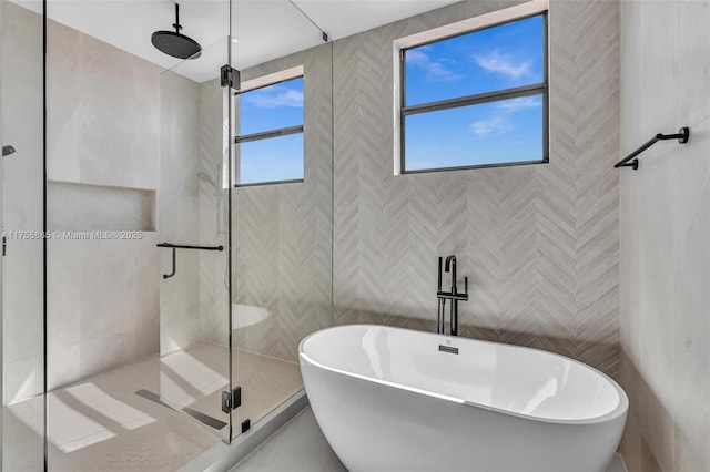 bathroom featuring a freestanding tub, a shower stall, and tile walls