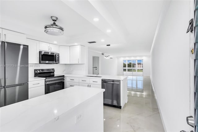 kitchen featuring white cabinets, appliances with stainless steel finishes, a peninsula, a sink, and recessed lighting