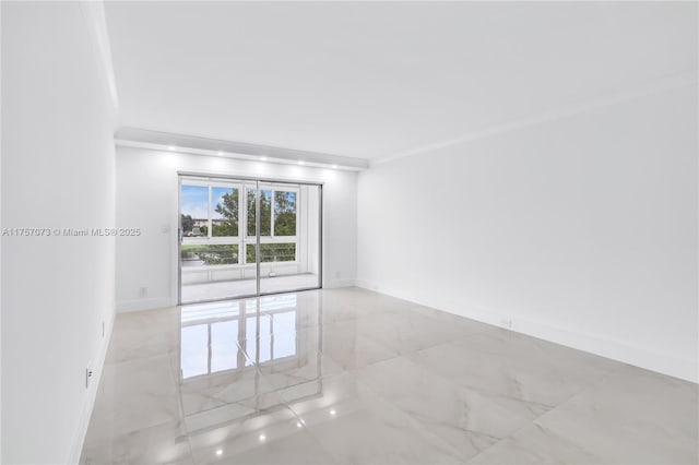 empty room with ornamental molding, marble finish floor, and baseboards