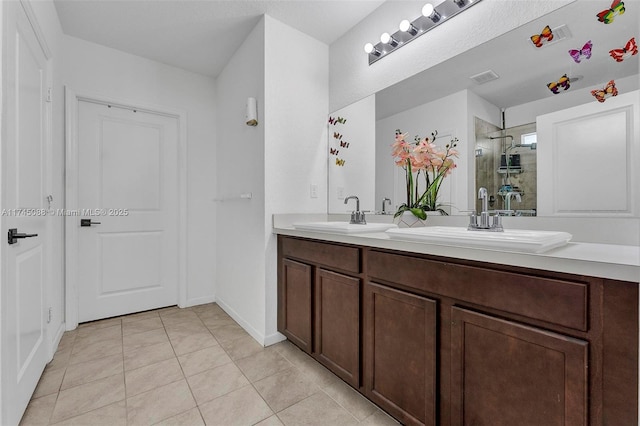 full bath featuring double vanity, a stall shower, tile patterned flooring, and a sink