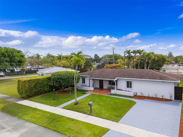 single story home featuring driveway, a front lawn, fence, and stucco siding