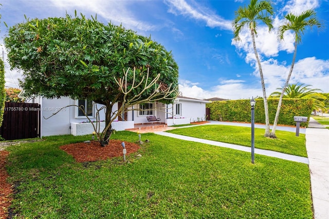 exterior space featuring fence, a front lawn, and stucco siding