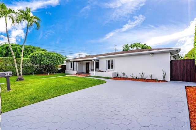 single story home featuring driveway, a front yard, fence, and stucco siding