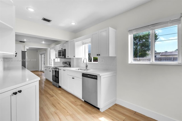 kitchen featuring visible vents, stainless steel appliances, light countertops, light wood-type flooring, and a sink