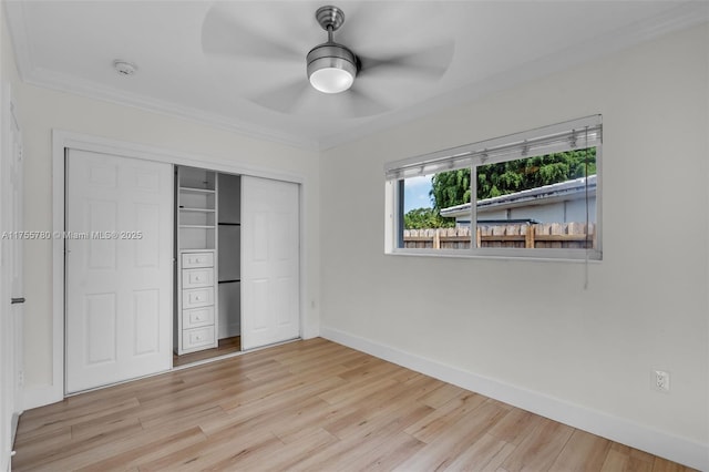 unfurnished bedroom with baseboards, light wood-style flooring, ceiling fan, crown molding, and a closet