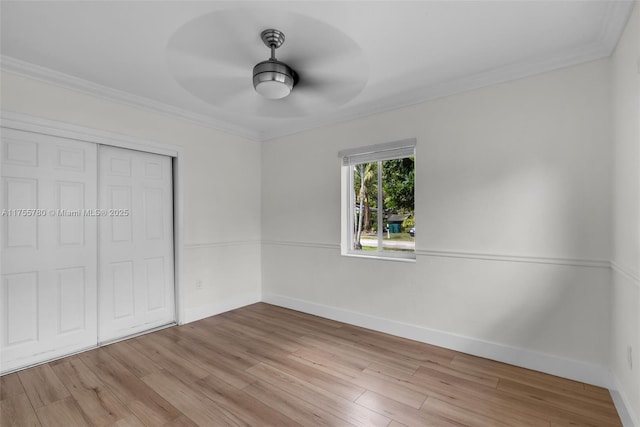 unfurnished bedroom featuring crown molding, a closet, baseboards, and wood finished floors