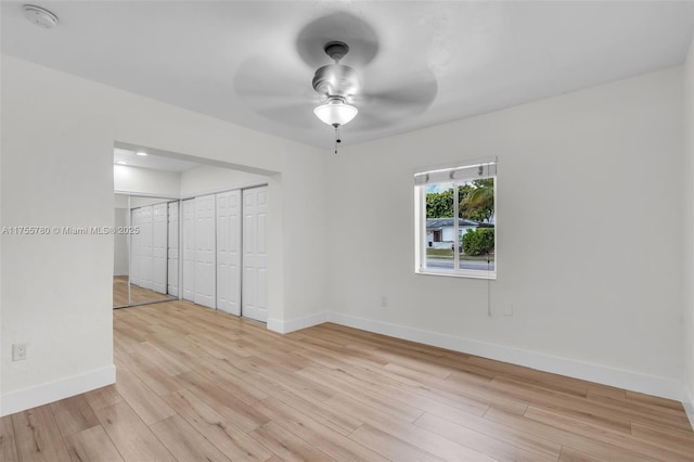 spare room featuring light wood finished floors, ceiling fan, and baseboards