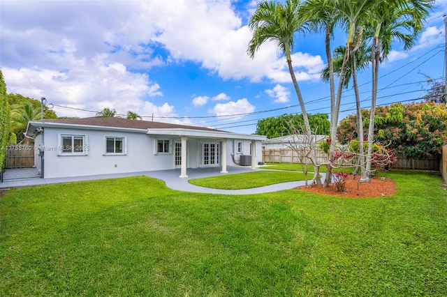 rear view of house featuring a fenced backyard, a yard, a patio, and stucco siding